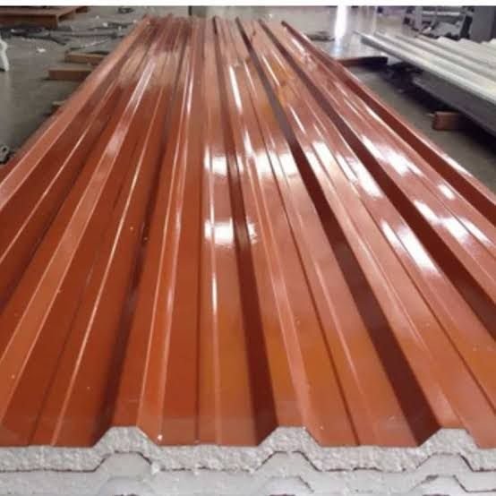 Telha sanduíche trapezoidal terracota com núcleo de EPS branco aparente na borda, empilhada na fábrica