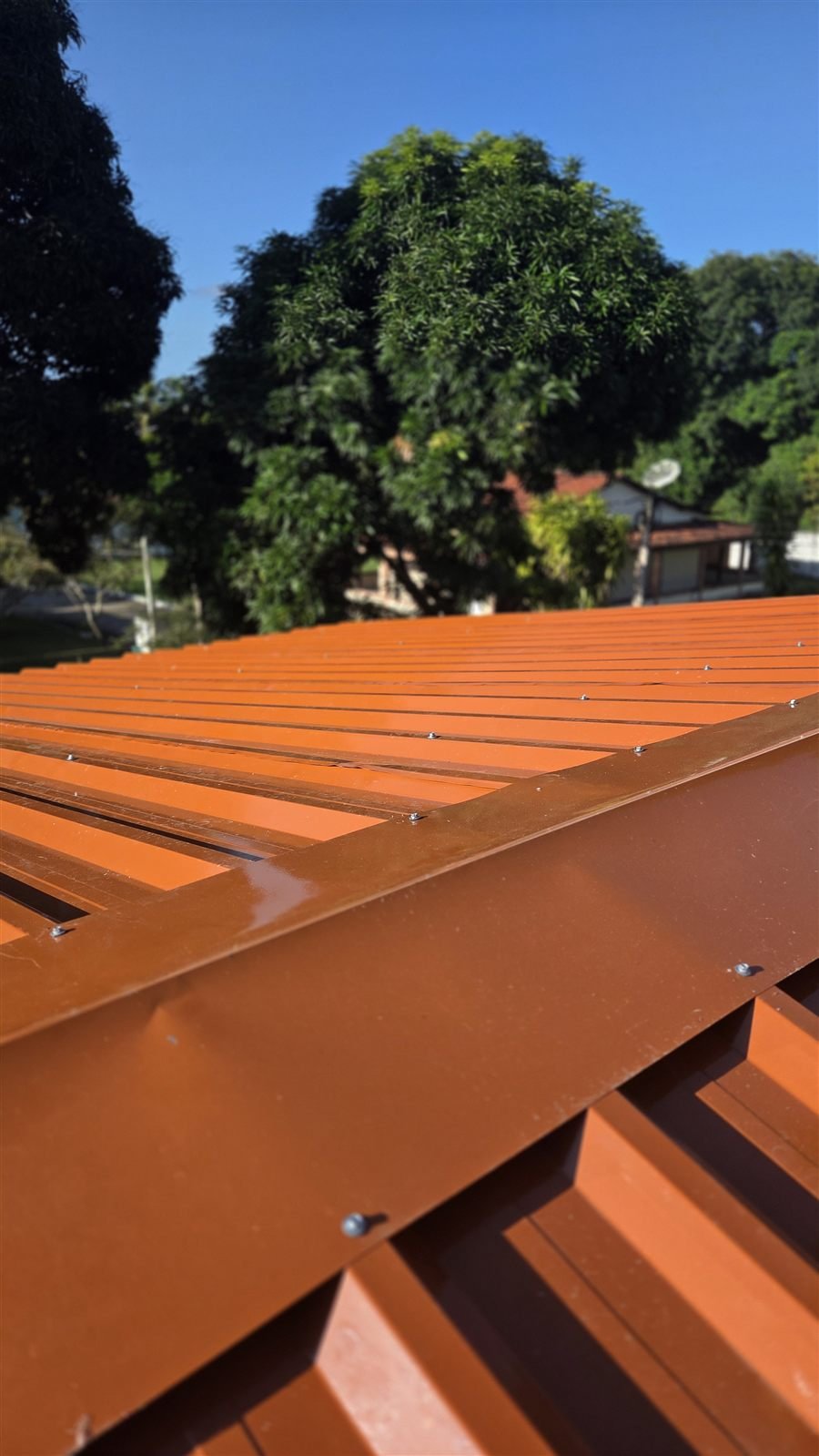 Telhado de telha trapezoidal terracota instalado, com cumeeira e fixação aparente